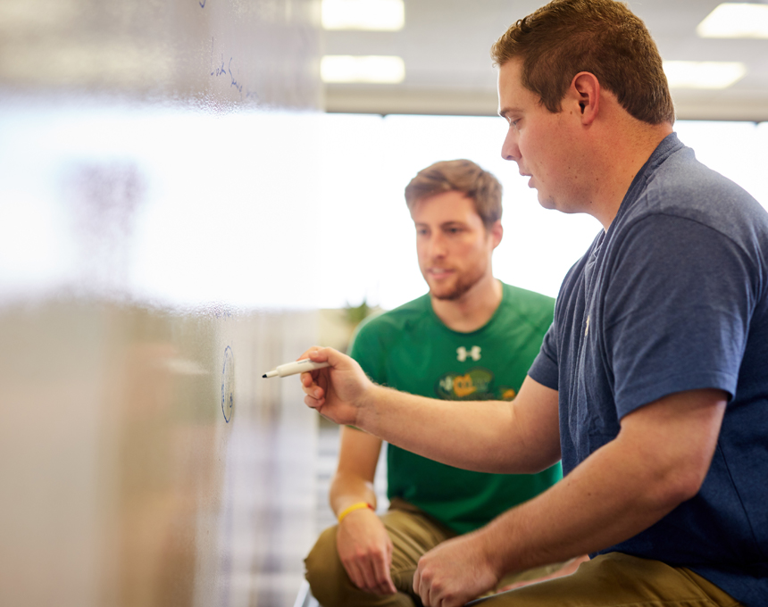 SAI employees working through a problem at a white board